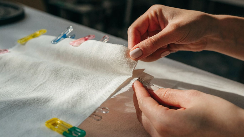 Hands aligning fabric layers with sewing clips and pins before stitching How to Pin and Clip Fabric Safely