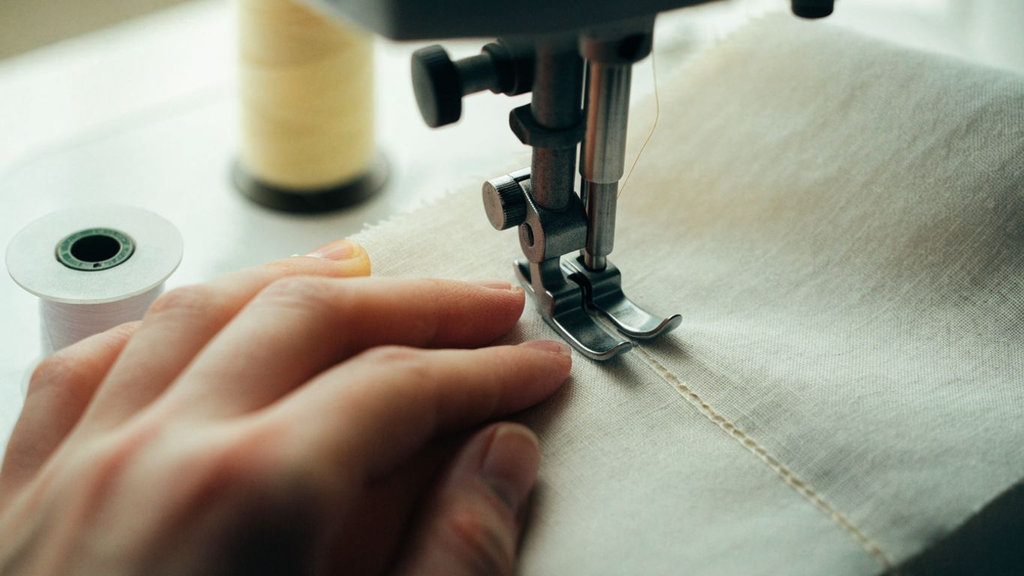 Beginner guiding fabric under a presser foot while practicing a straight sewing machine seam How to Use a Sewing Machine Step by Step